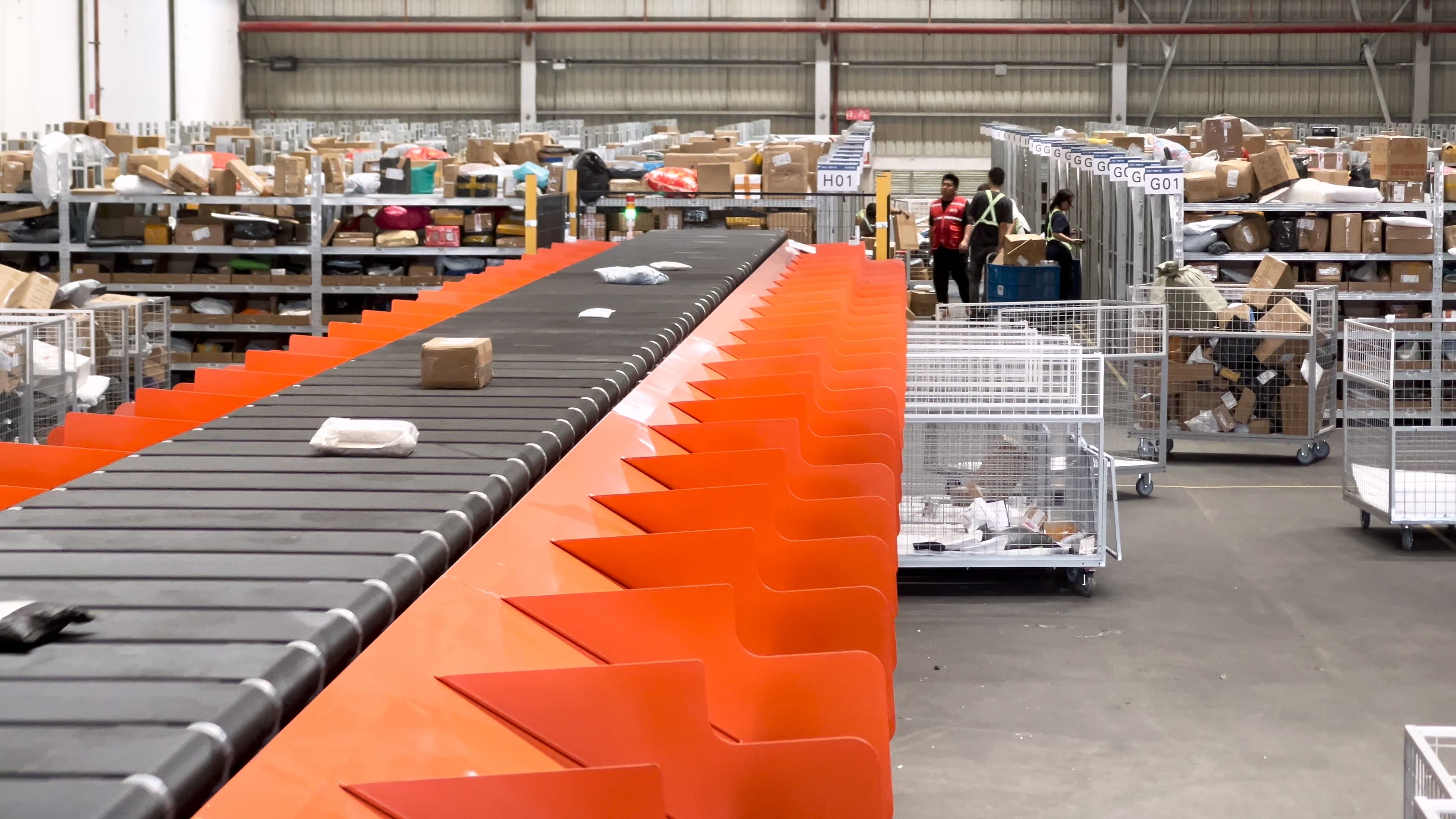 Orange narrow-belt parcel sorter handling parcels in an operating distribution facility